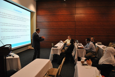 Yakovlev stands presenting a powerpoint presentation at the front of a room